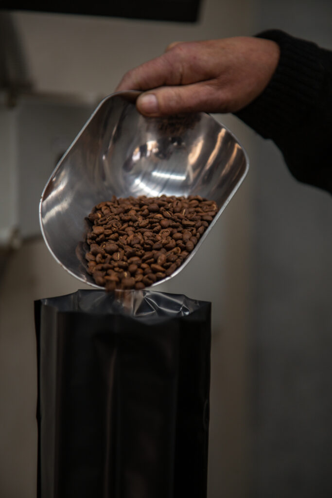 coffee beans being poured from metal scoop