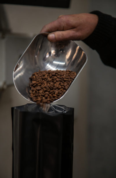 coffee beans being poured from metal scoop