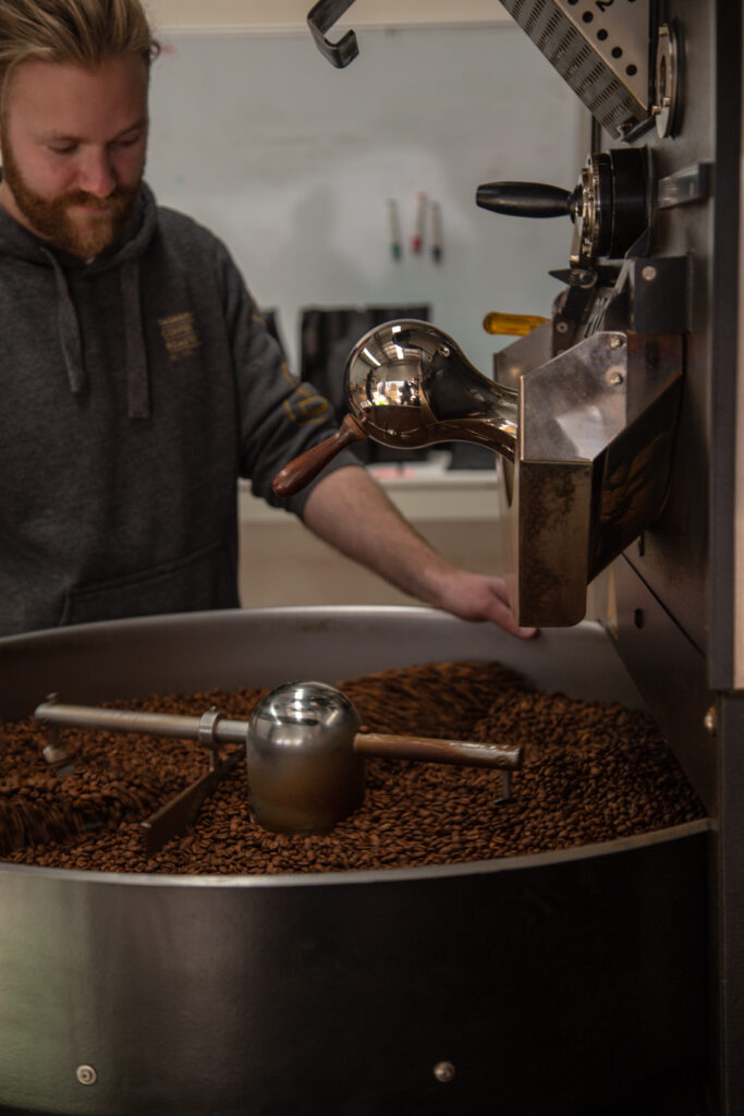 man with beard operating coffee roasting machine