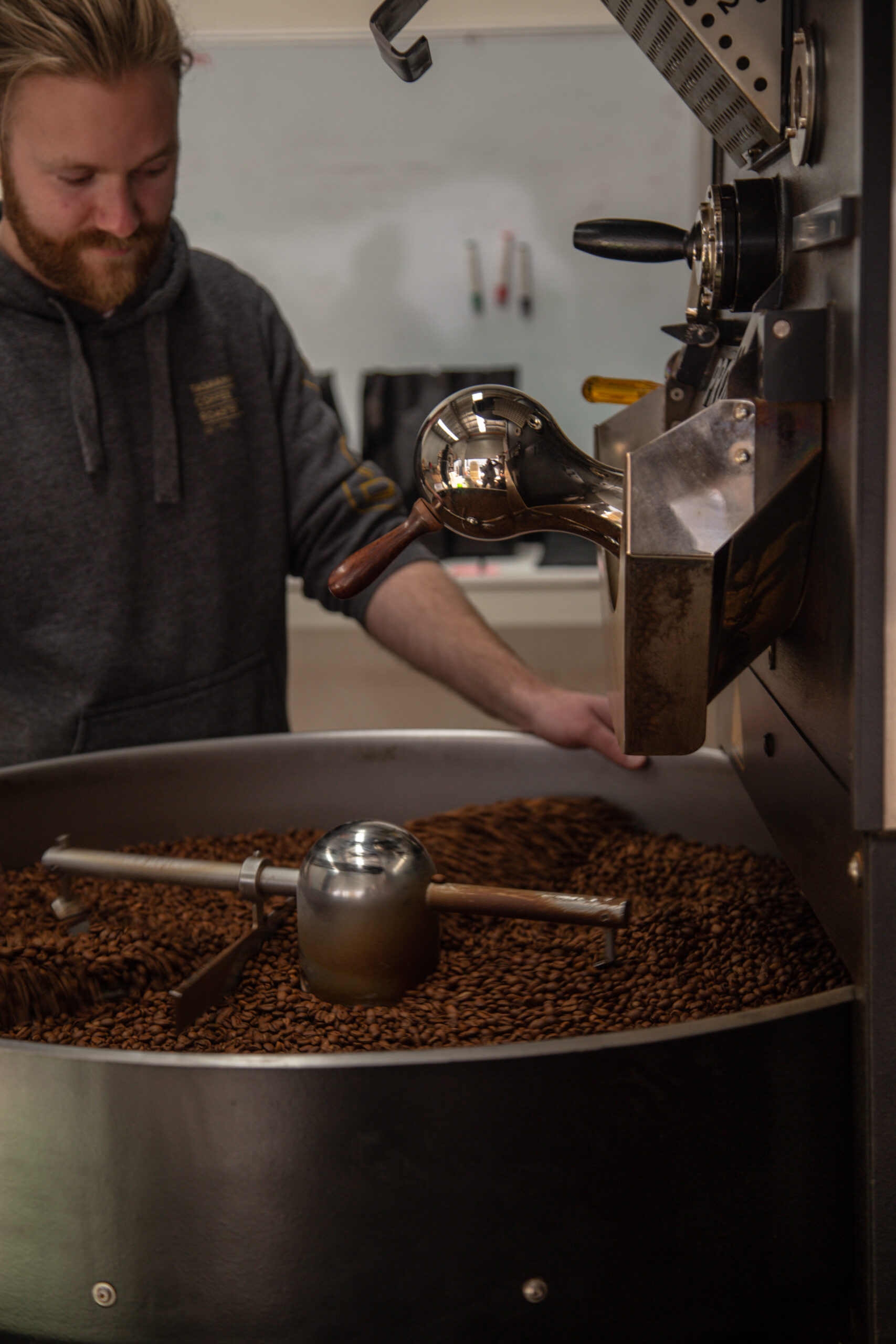 man with beard operating coffee roasting machine